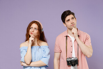 Two pensive thoughtful traveler tourist woman man couple in summer clothes look aside prop up chin isolated on purple background Passenger travel abroad on weekends getaway Air flight journey concept