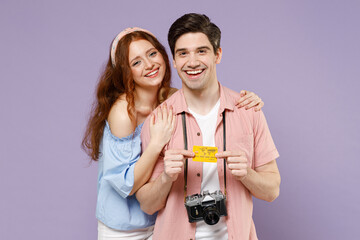 Two smiling happy traveler tourist woman man couple in shirt hold credit bank card look camera hug isolated on purple background Passenger travel abroad on weekends getaway Air flight journey concept.