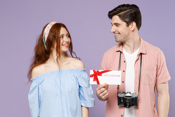 Two traveler tourist woman man couple in shirt hold gift voucher flyer mock up look to each other isolated on purple background Passenger travel abroad on weekends getaway Air flight journey concept.