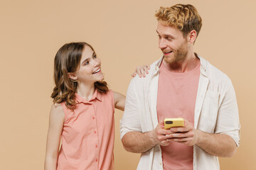 Young parent man with child teen girl in casual pastel clothes. Daddy little kid daughter using mobile cell phone looking to each other isolated on beige background. Father's Day Love family concept