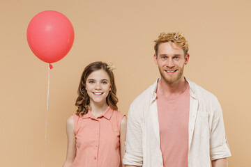 Young happy parent man with child teen girl wear casual clothes Daddy kid daughter celebrating birthday holiday party and holding red air inflated helium balloon isolated on beige background studio
