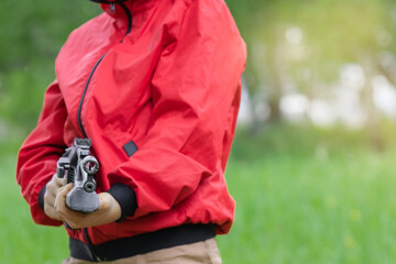 Focus on the sight and the muzzle of an airgun in the hands of a boy in a red windbreaker. The concept of weapons and children, training in shooting. Copy space.