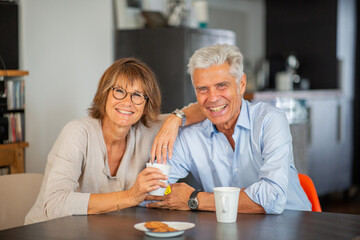smiling mature couple sitting at table with cup of tea