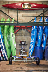 A row of colourful sit on top kayaks either side of a boat towing winch cart
