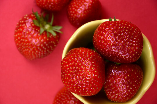 Strawberries in a bowl top view close-up stock images. Pile of fresh ripe strawberries on a red background stock photo