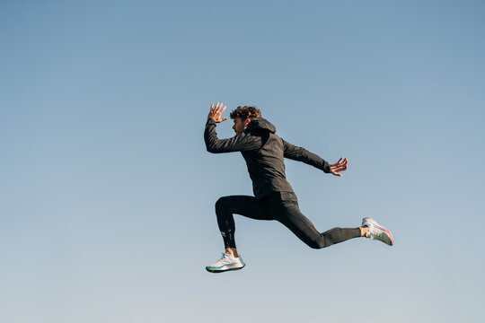 Fast runner jumping during workout under blue sky