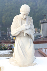 Naklejka premium Valenciennes, France, 2017/01/02. Statue of a young girl with a candle on a tombstone at Saint Roch cemetery.