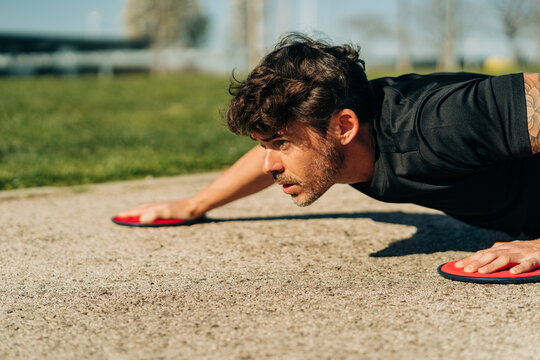 Determined sportsman working out with exercise discs in park