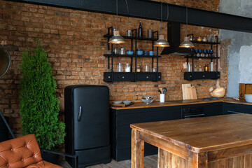 Side view on a wooden table and open space industrial loft kitchen with vintage decor and black cabinets