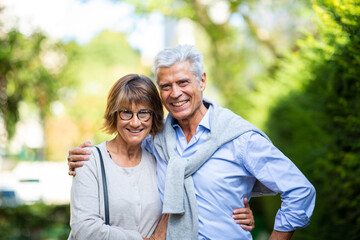 smiling older couple standing outside in park