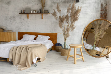 Top view of pacious airy white industrial loft bedroom with bed,  mirror and pampas grass decoration
