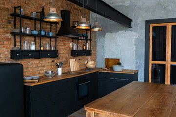 View on a wooden table and open space industrial loft kitchen with vintage decor and black cabinets