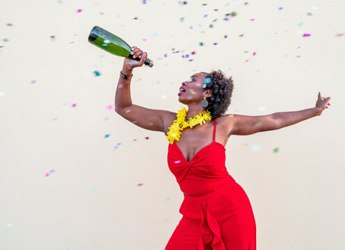 Happy black woman with glass bottle of champagne