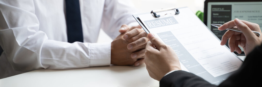 Examiner Reading A Resume During Job Interview At Office