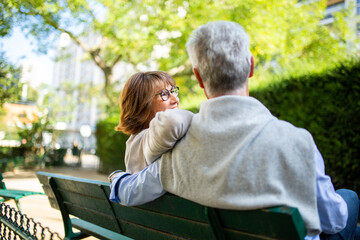 back of couple sitting on park bench