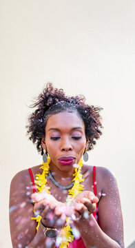 Black woman blowing on flower petals during celebration