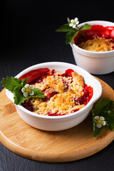 Food concept rustic summer strawberry crumble on black background with copyspace
