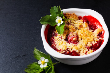 Food concept rustic summer strawberry crumble on black background with copyspace