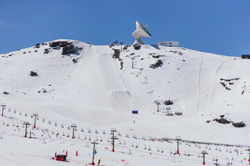 Observatory on snowy ridge against house exterior in ski resort