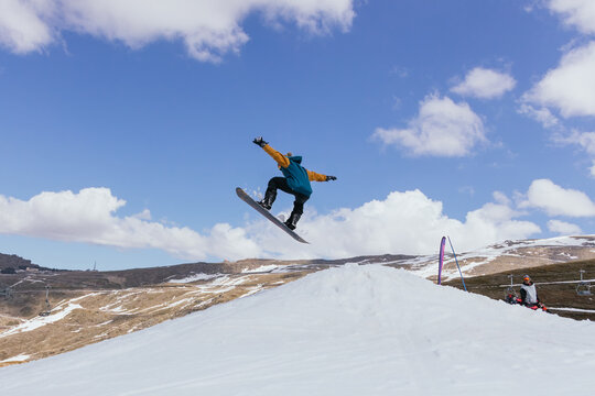 Unrecognizable sportsman riding snowboard in winter mountains