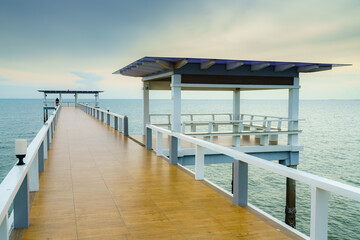 Sea or nature background with sunset and sky at twilight. Perspective view of wood bridge and pavilion. Asia travel destination in Chonburi of Thailand called Bangsaen Beach for holiday and vacation.