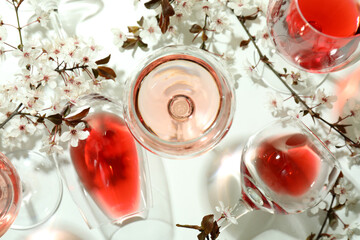 Glasses of wine and cherry flowers on white background