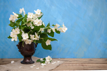 A bouquet of jasmine in a brown vase on a blue background