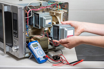 Repair of the microwave oven. The woman shows the new magnetron.