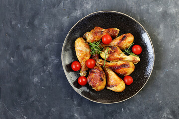 Fried chicken legs with spices in a plate on a black background top view.
