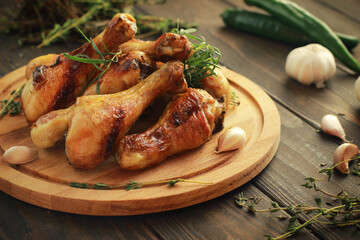 Fried chicken legs with spices on the board on a wooden table.