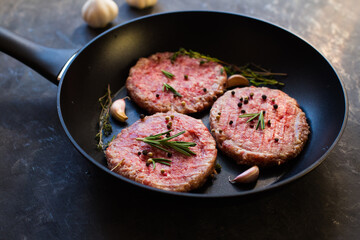 Raw beef meat burger steak cutlets in the pan on the black table.