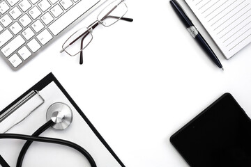 Medical stethoscope, keyboard, notebook with pen and black tablet on white background. Doctor's workplace. Top view. Flatlay composition. Medical concept.
