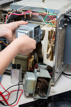 Repair of the microwave oven. A woman replaces a magnetron.