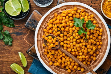 Fried chickpeas with turmeric in ceramic plate on an old wooden table background. Roasted spicy chickpeas or Indian chana or chole, popular snack recipe. Top view.