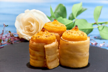 Artisan sweets made in the bakery. Cakes with egg yolk, flour and sugar with natural decoration of plants and blue background.