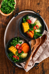 Chilean meat soup with pampkin, corn, fresh coriander and potatoes on old wooden table background. Cazuela. Latinamerican food.