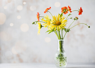Beautiful yellow and red wildflowers on a light background with bokeh and copy space. Summer natural background.