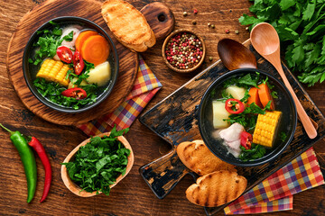 Chilean meat soup with pampkin, corn, fresh coriander and potatoes on old wooden table background. Cazuela. Latinamerican food.