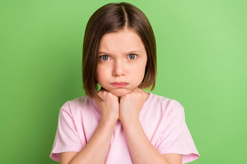 Photo of young little girl unhappy sad upset hand touch chin bored offended isolated over green...