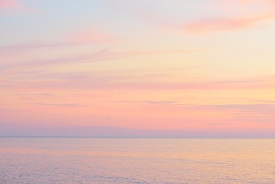 Baltic sea at sunset. Dramatic sky, blue and pink glowing clouds, soft golden sunlight, midnight sun. Picturesque dreamlike seascape, cloudscape, nature. Panoramic view