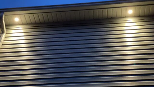 Outdoor pot lights on exterior of house lighting up outside of home with vinyl siding during evening
