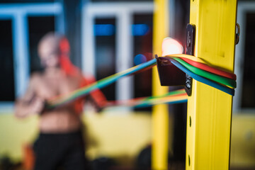 Colorful resistance bands close up with bodybuilder in the background