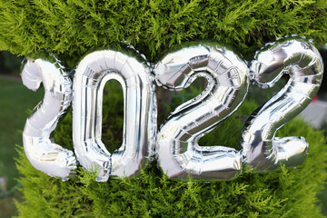 Number 2022 of silver helium balloons hanging on christmas tree closeup