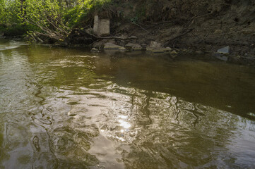 Obraz na płótnie Canvas Photo of a small river (stream) polluted with broken concrete slabs.