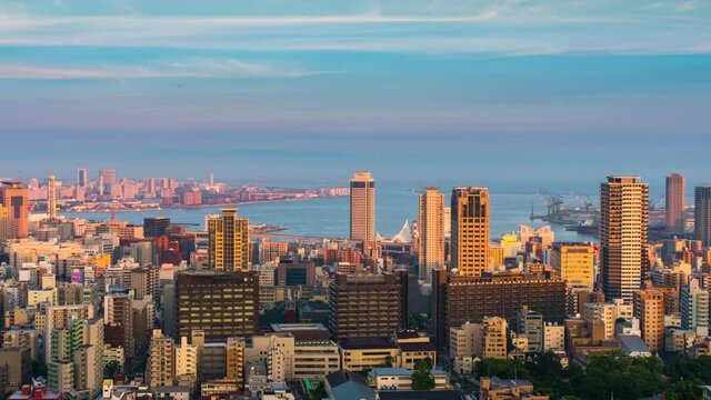 Kobe, Japan. Aerial view of downtown Kobe, Japan at sunset. Time-lapse of the colorful sky with boats at the harbor and numerous skyscrapers, zoom in