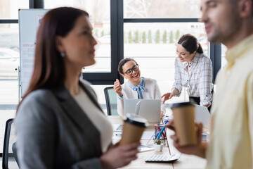 African american businesswoman looking at laptop near colleague pointing with finger