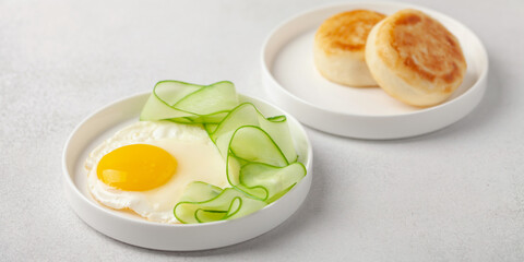 Eggs, cucumber in a plate and curd pancakes on the table.  Healthy breakfast