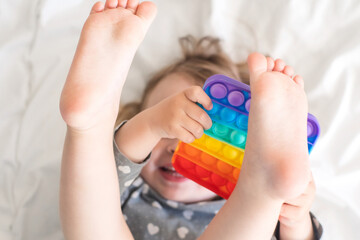a small child is playing a modern anti-stress pop it toy. baby plays rubber educational toy at home