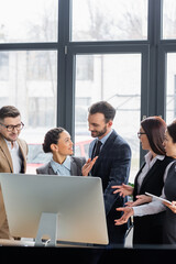 Fototapeta premium African american businesswoman pointing at colleague near computer in office