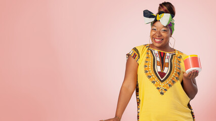 Portrait of a black woman holding a product smiling looking at camera.